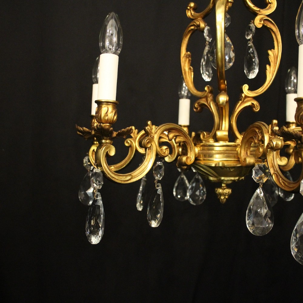 A French gilt bronze six-light chandelier decorated with scrolling arms and suspended cut crystal teardrop pendants. View II