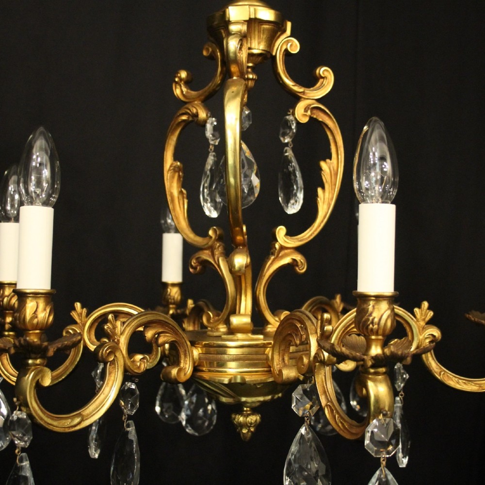 A French gilt bronze six-light chandelier decorated with scrolling arms and suspended cut crystal teardrop pendants. View III