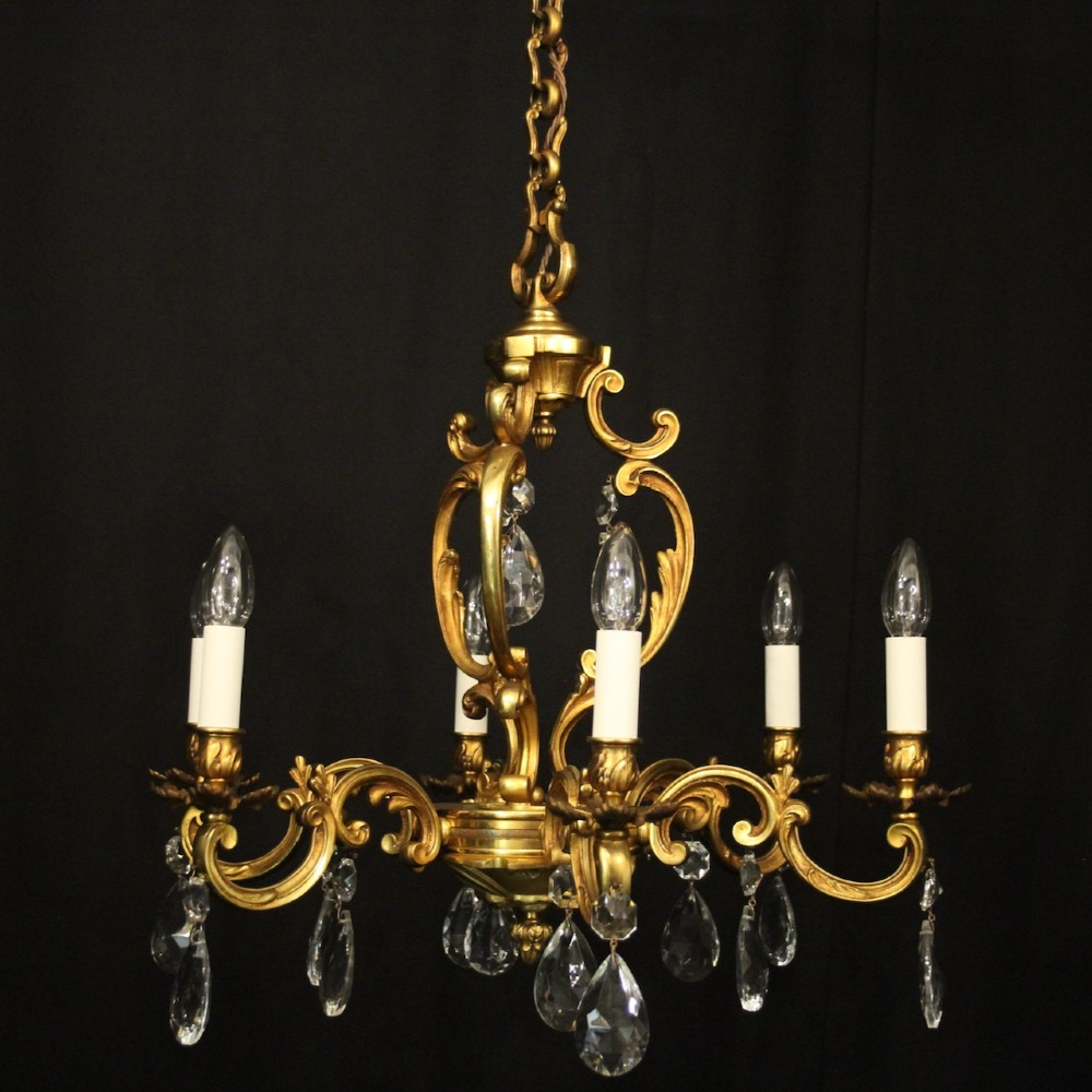 A French gilt bronze six-light chandelier decorated with scrolling arms and suspended cut crystal teardrop pendants. View IV