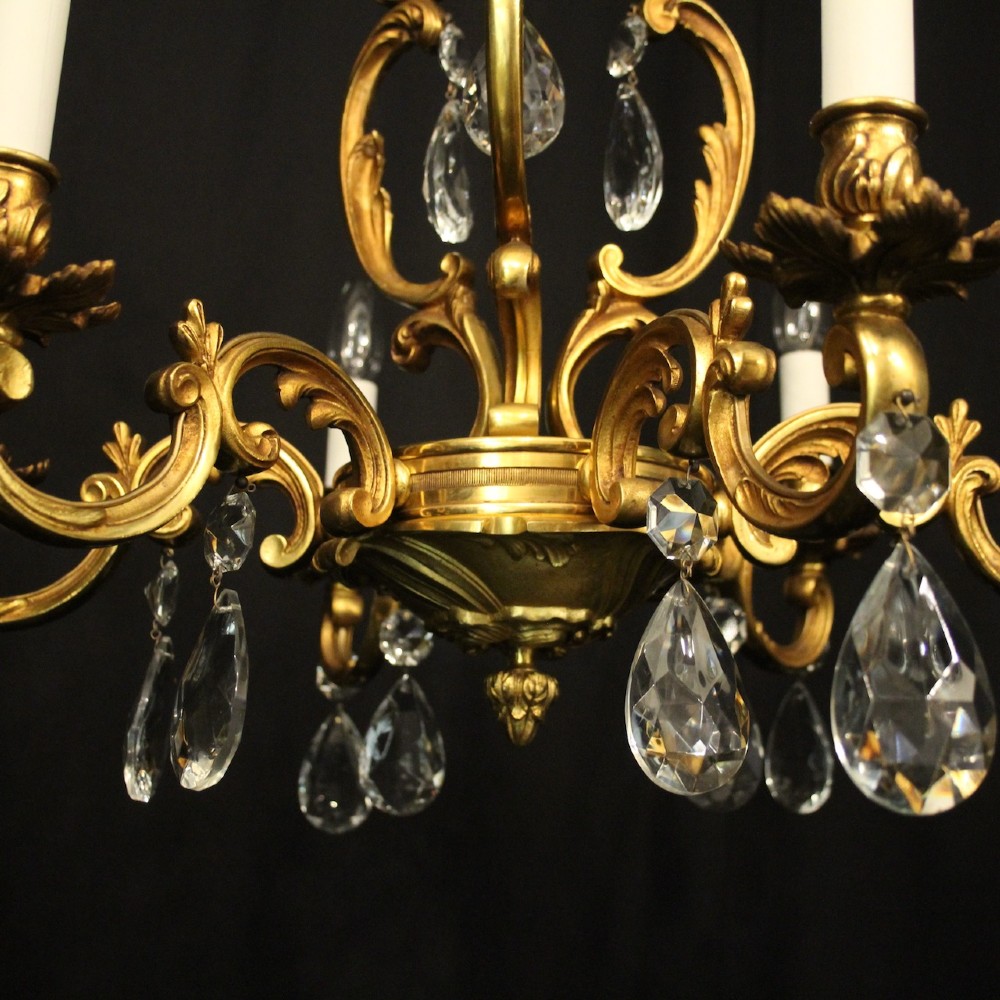 A French gilt bronze six-light chandelier decorated with scrolling arms and suspended cut crystal teardrop pendants. View VI