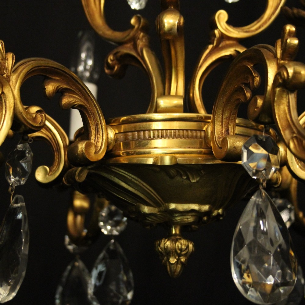 A French gilt bronze six-light chandelier decorated with scrolling arms and suspended cut crystal teardrop pendants. View VII