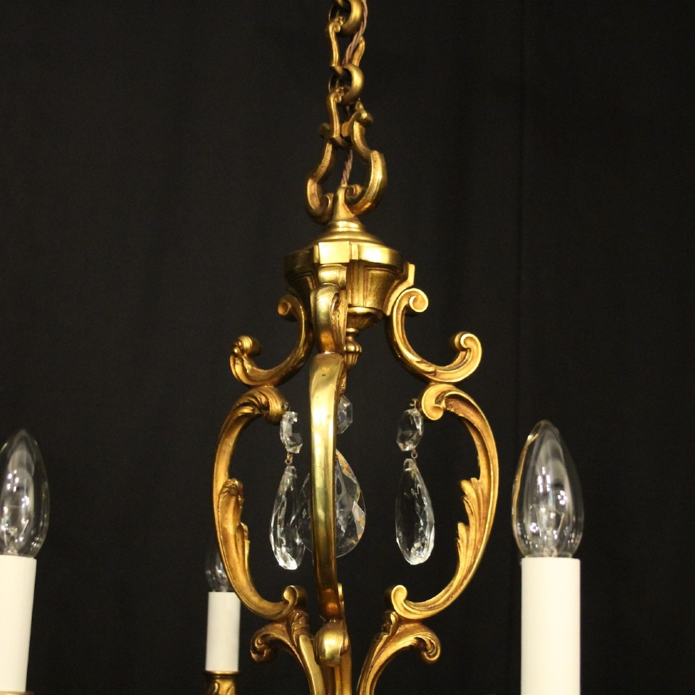 A French gilt bronze six-light chandelier decorated with scrolling arms and suspended cut crystal teardrop pendants. View VIII