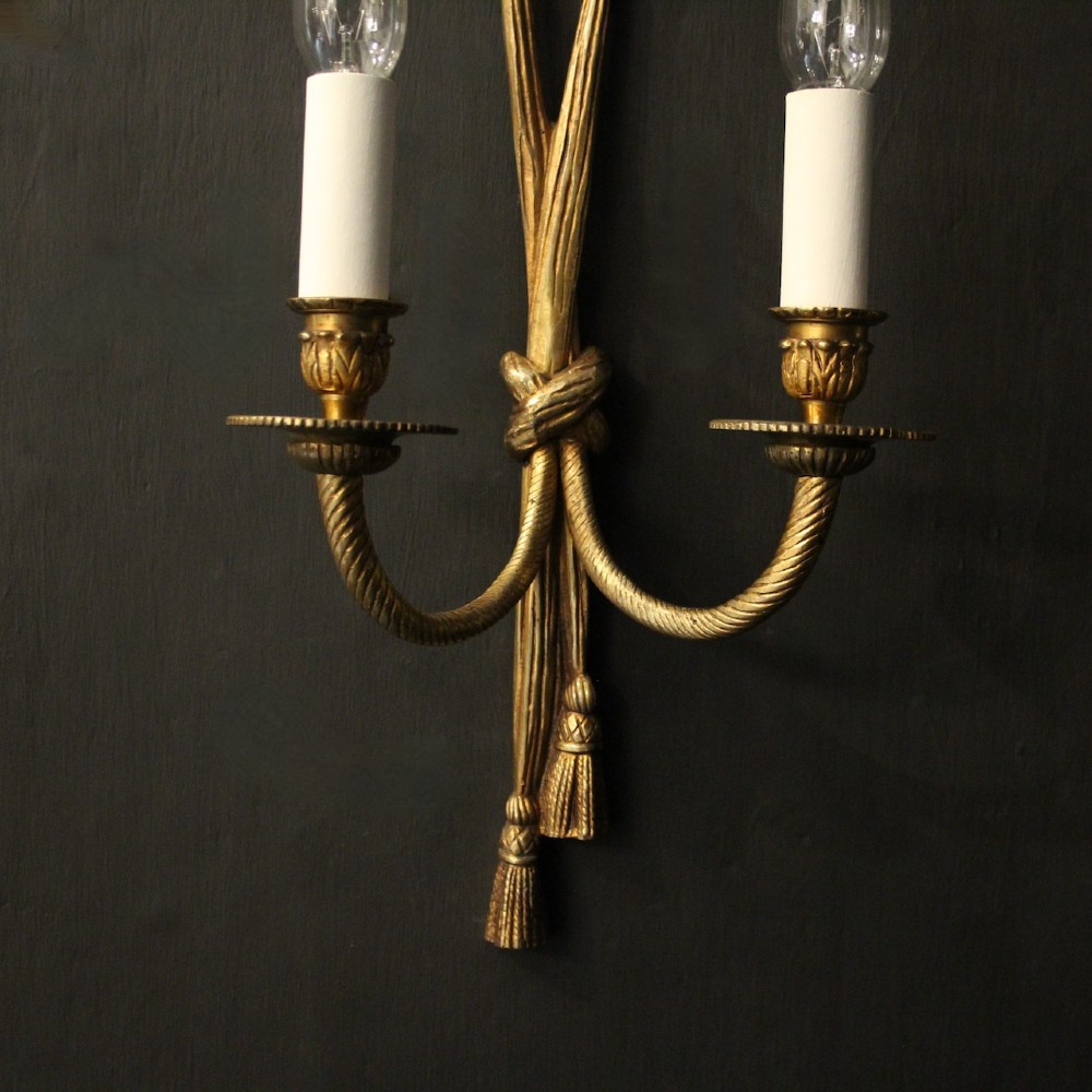 A pair of French gilded brass twin-arm wall sconces featuring a tied rope and tassel motif with candle-style bulb fittings. View III