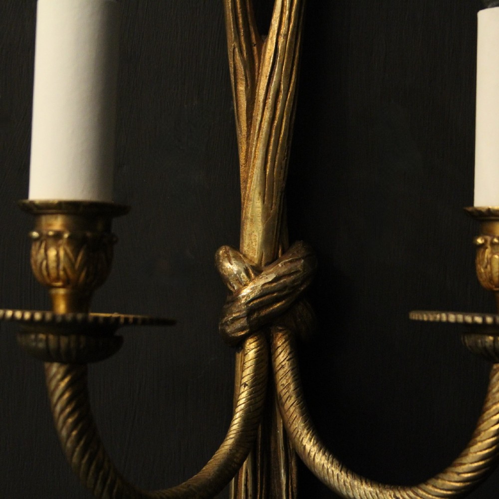 A pair of French gilded brass twin-arm wall sconces featuring a tied rope and tassel motif with candle-style bulb fittings. View V