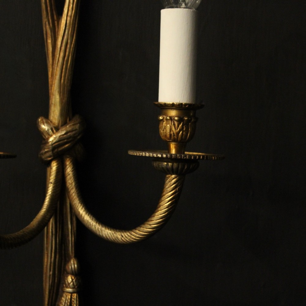 A pair of French gilded brass twin-arm wall sconces featuring a tied rope and tassel motif with candle-style bulb fittings. View VII