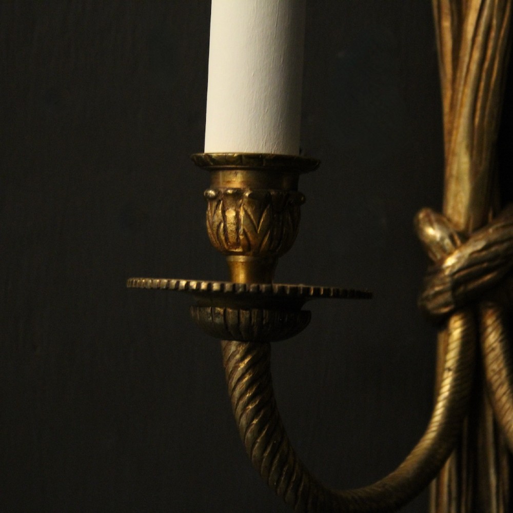 A pair of French gilded brass twin-arm wall sconces featuring a tied rope and tassel motif with candle-style bulb fittings. View VIII