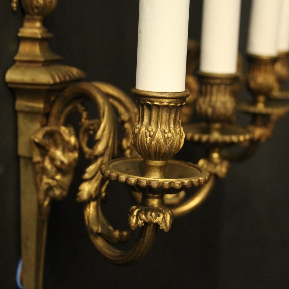 A pair of antique gilded bronze two-arm wall lights decorated with central urn finials and acanthus leaf scroll branches. View VI