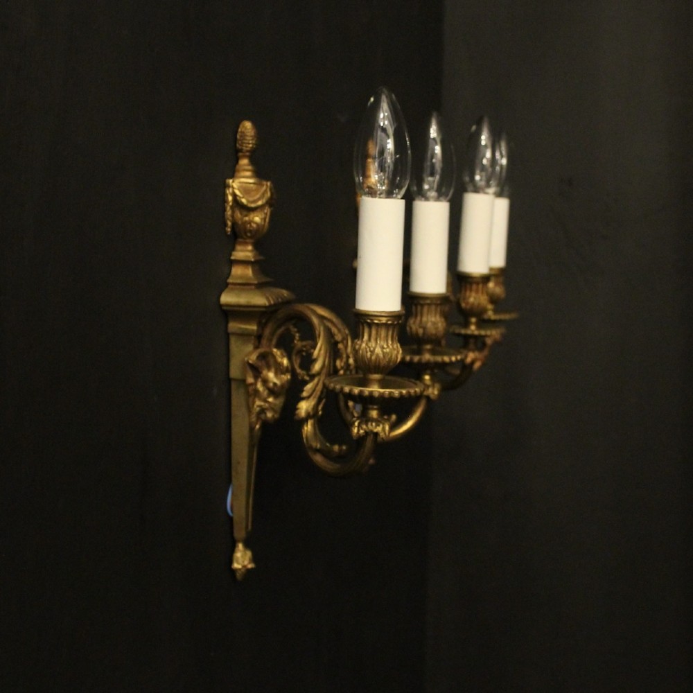 A pair of antique gilded bronze two-arm wall lights decorated with central urn finials and acanthus leaf scroll branches. View X