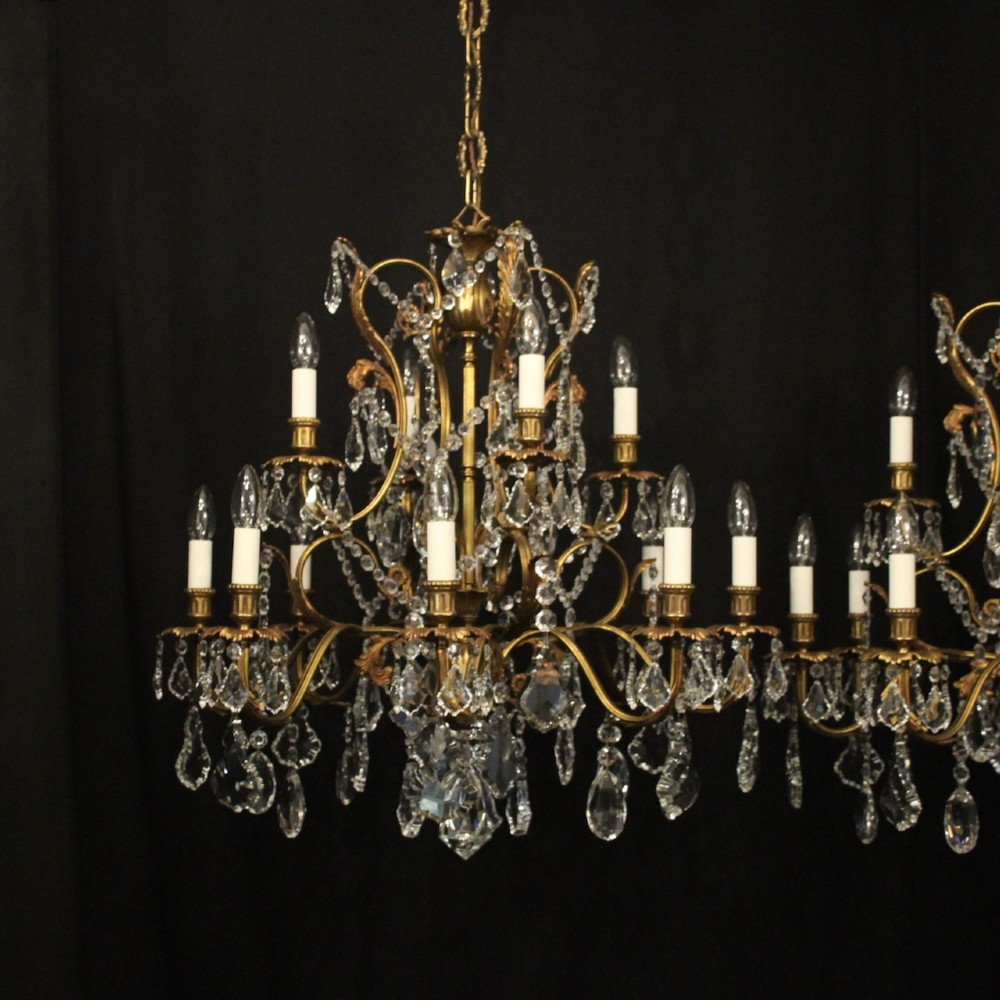 A pair of twelve-light French chandeliers made from gilt metal frames heavily decorated with hanging faceted crystal drops and candleshaft bulb holders. View II