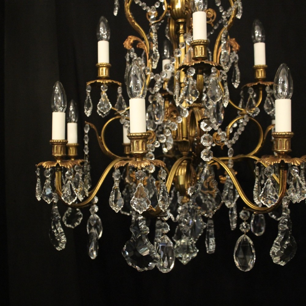 A pair of twelve-light French chandeliers made from gilt metal frames heavily decorated with hanging faceted crystal drops and candleshaft bulb holders. View III