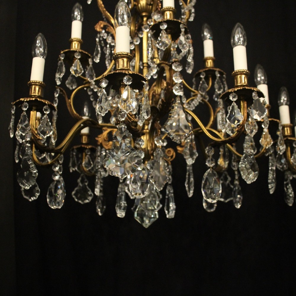 A pair of twelve-light French chandeliers made from gilt metal frames heavily decorated with hanging faceted crystal drops and candleshaft bulb holders. View IV