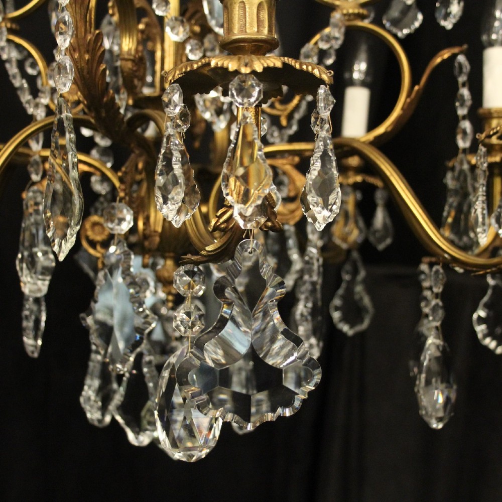 A pair of twelve-light French chandeliers made from gilt metal frames heavily decorated with hanging faceted crystal drops and candleshaft bulb holders. View V