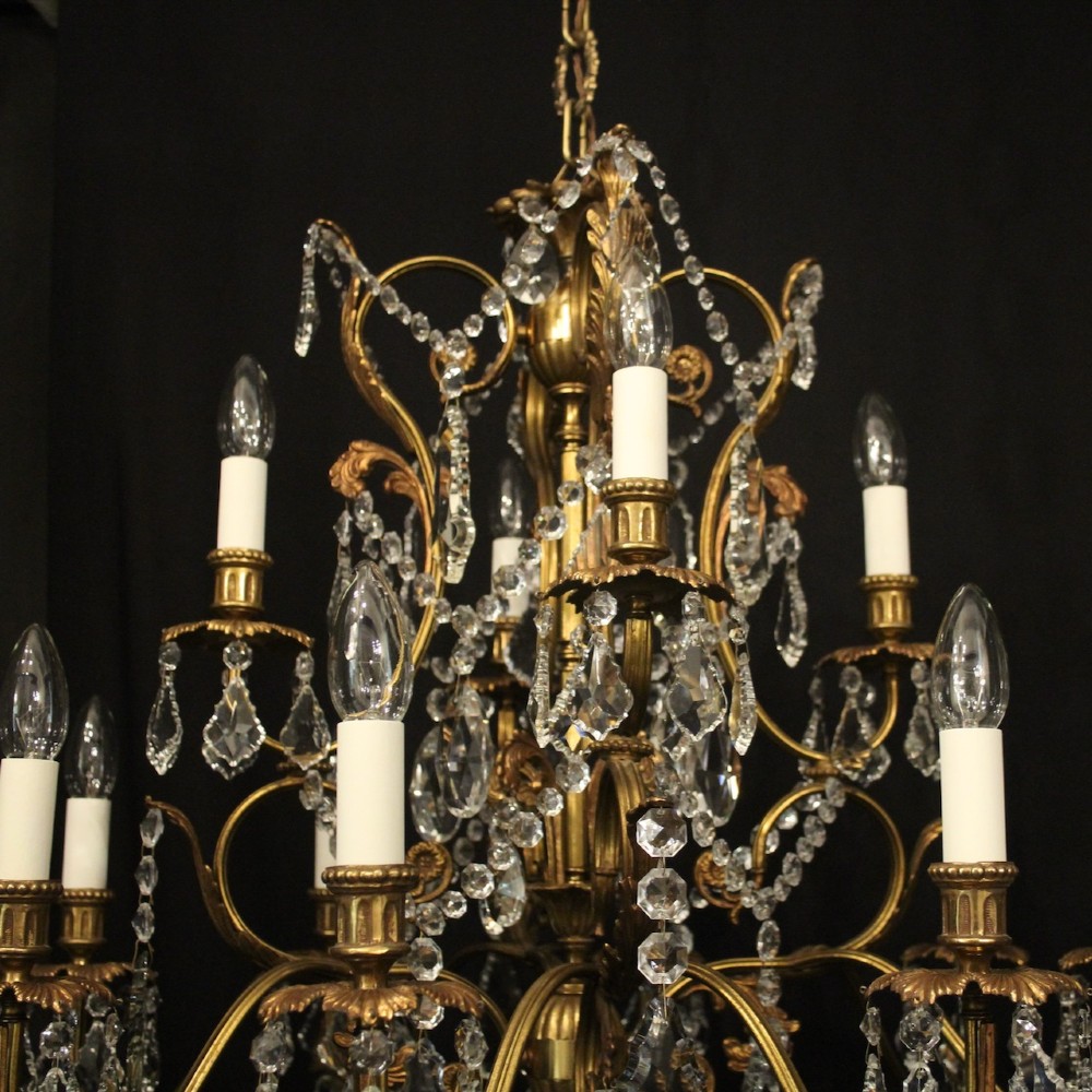 A pair of twelve-light French chandeliers made from gilt metal frames heavily decorated with hanging faceted crystal drops and candleshaft bulb holders. View VI