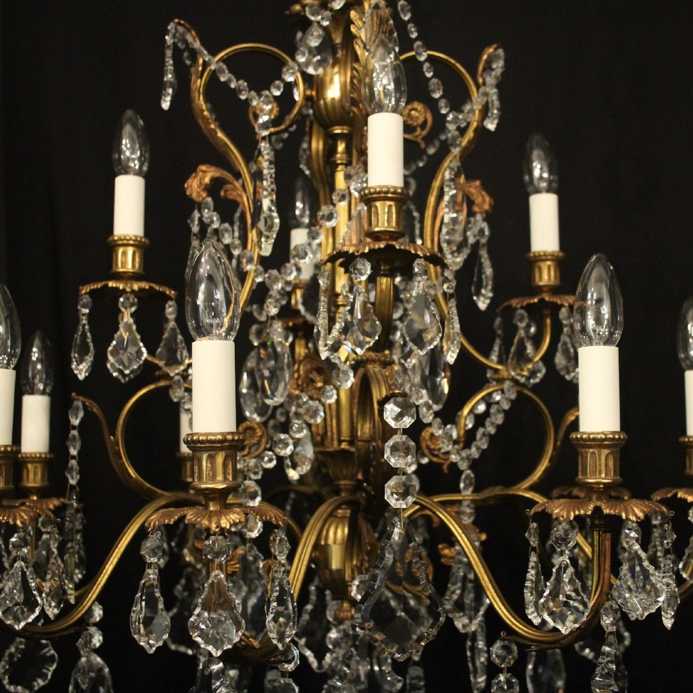 A pair of twelve-light French chandeliers made from gilt metal frames heavily decorated with hanging faceted crystal drops and candleshaft bulb holders. View VII
