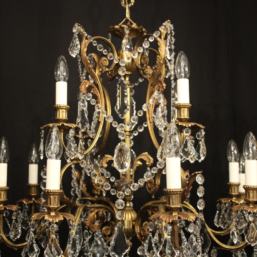 A pair of twelve-light French chandeliers made from gilt metal frames heavily decorated with hanging faceted crystal drops and candleshaft bulb holders. View VIII