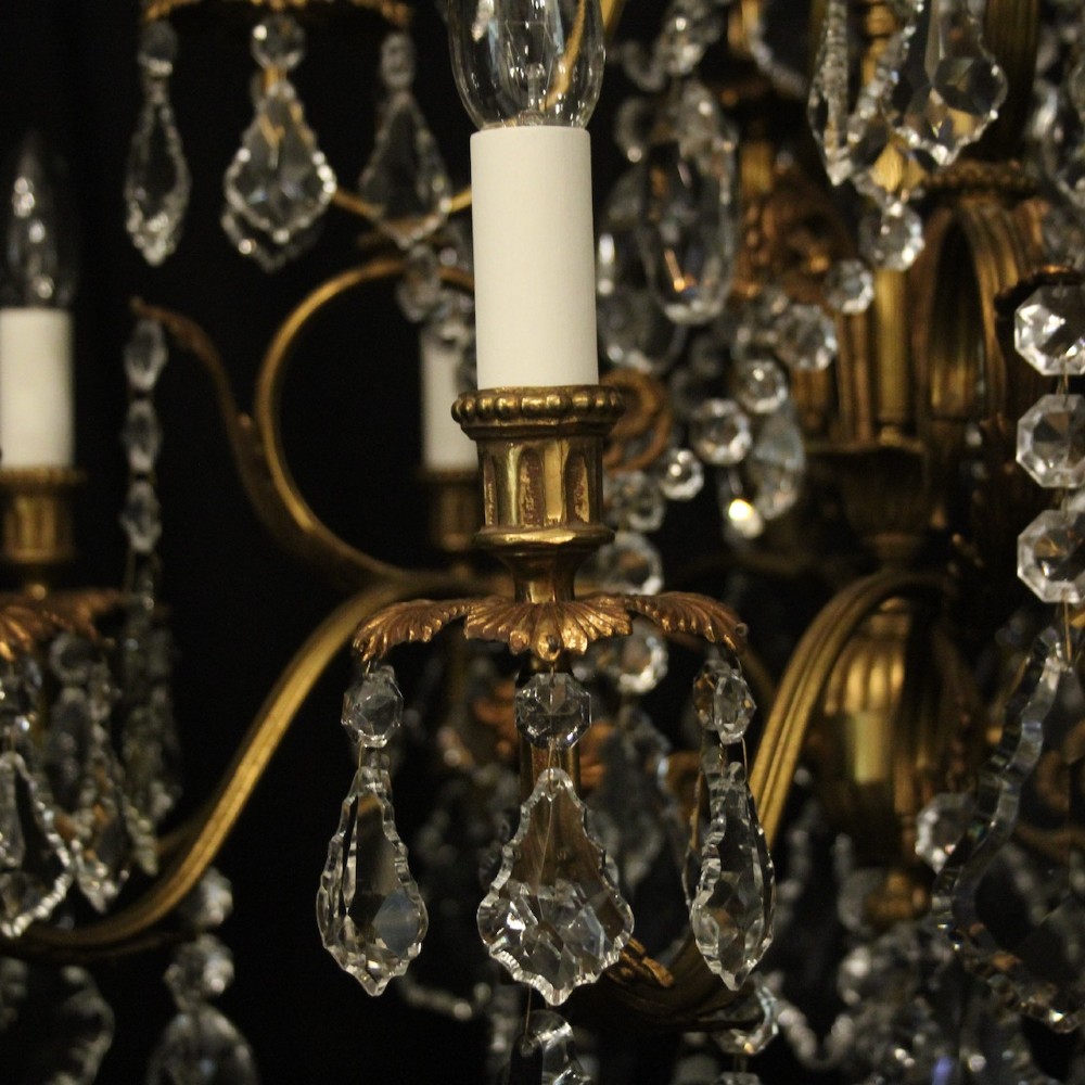 A pair of twelve-light French chandeliers made from gilt metal frames heavily decorated with hanging faceted crystal drops and candleshaft bulb holders. View IX