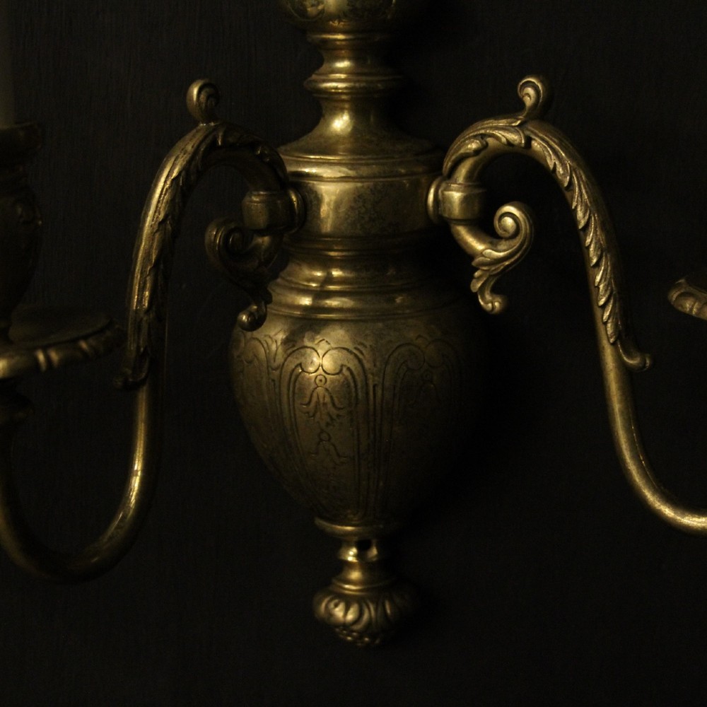 A pair of antique bronze twin-arm wall lights with urn-shaped central bodies and decorative scroll arms against a dark backdrop. View VII
