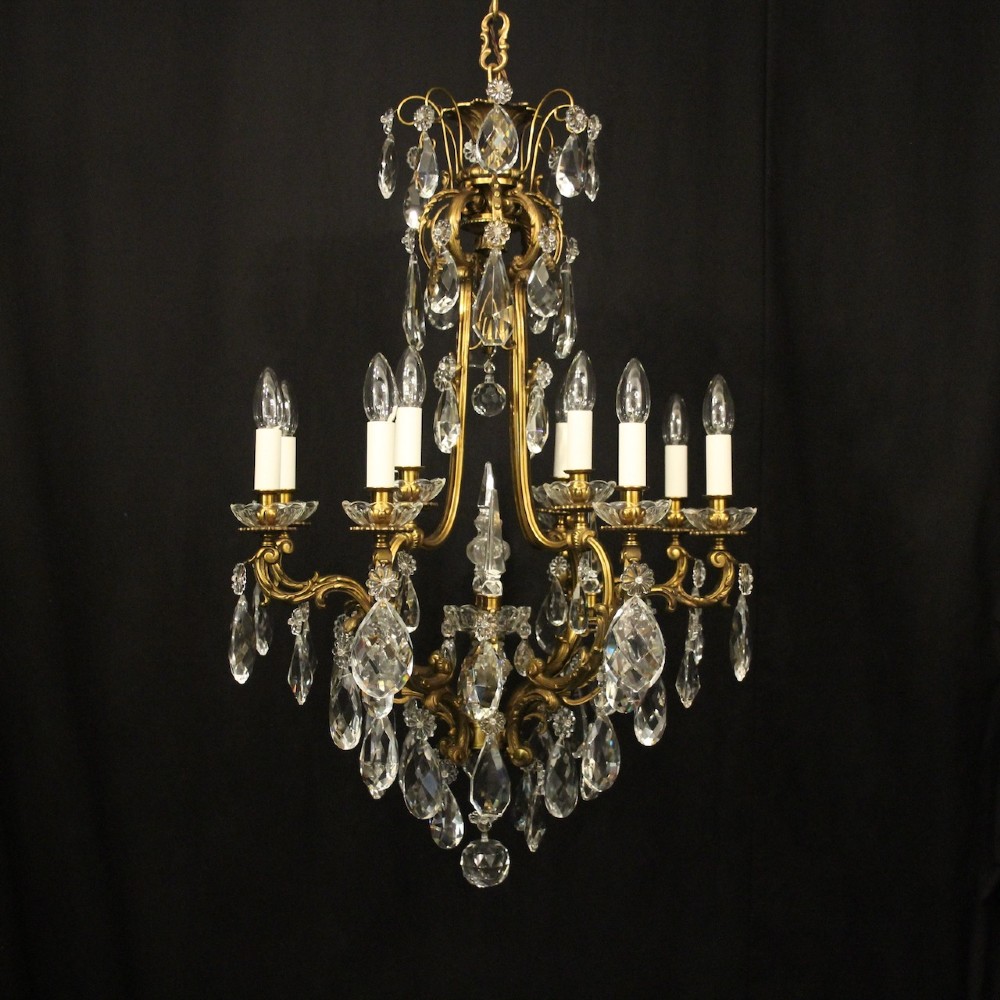 A French gilded bronze cage chandelier featuring scrolled arms, candle-style bulb holders, and hanging cut crystal drops.