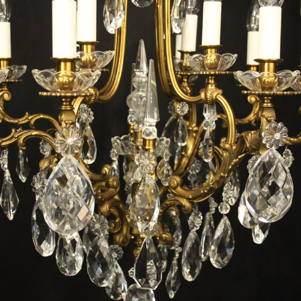 A French gilded bronze cage chandelier featuring scrolled arms, candle-style bulb holders, and hanging cut crystal drops. View IV