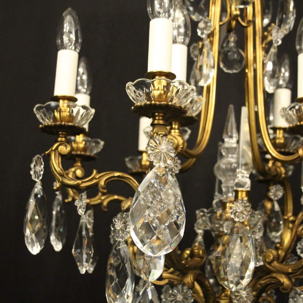 A French gilded bronze cage chandelier featuring scrolled arms, candle-style bulb holders, and hanging cut crystal drops. View V
