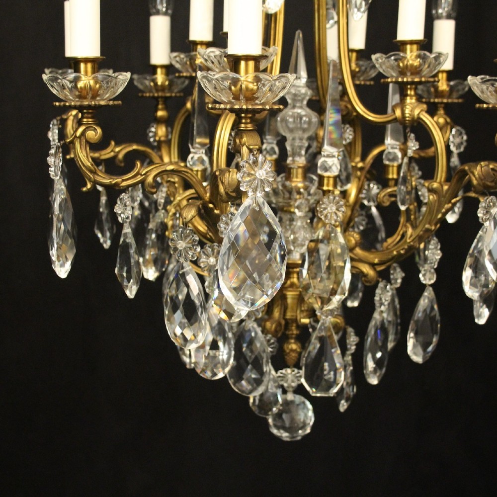 A French gilded bronze cage chandelier featuring scrolled arms, candle-style bulb holders, and hanging cut crystal drops. View VI