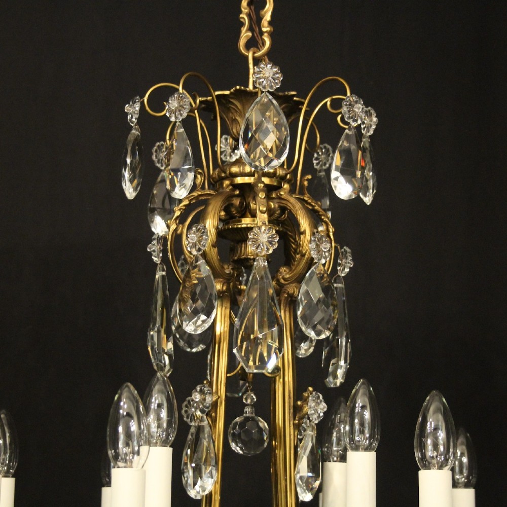 A French gilded bronze cage chandelier featuring scrolled arms, candle-style bulb holders, and hanging cut crystal drops. View IX