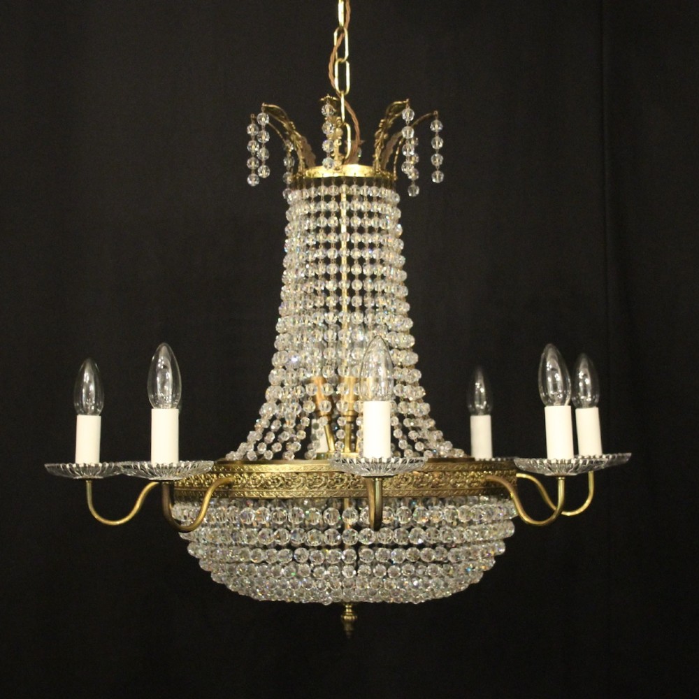 A French gilded brass fifteen-light waterfall chandelier featuring cascading crystal beads, a detailed metal gallery band, and radiating candle arms.
