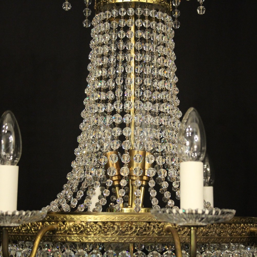 A French gilded brass fifteen-light waterfall chandelier featuring cascading crystal beads, a detailed metal gallery band, and radiating candle arms. View VI