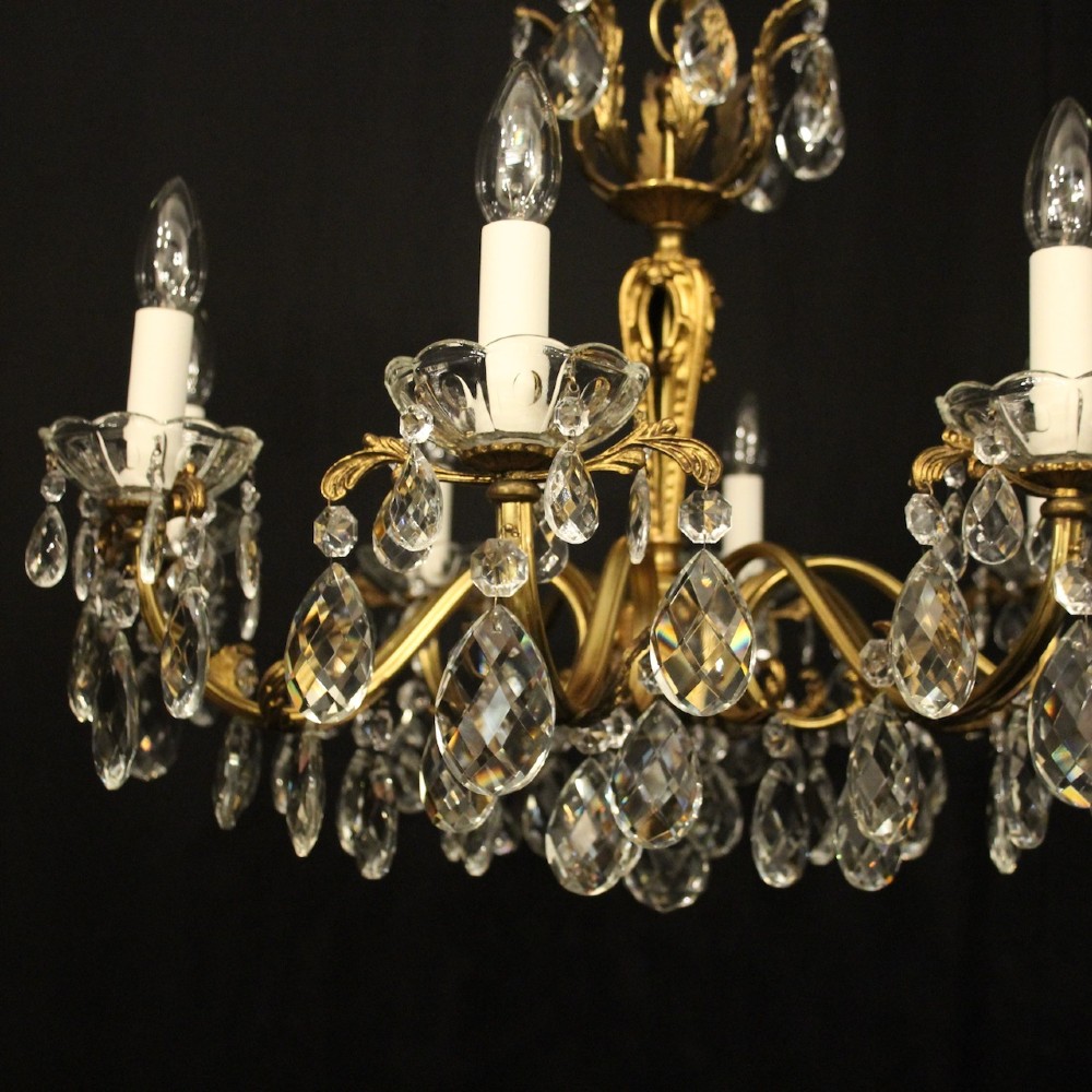 An eight-arm French chandelier featuring a gilded brass frame decorated with hanging cut-crystal glass drops and white candle-style bulb holders. View III