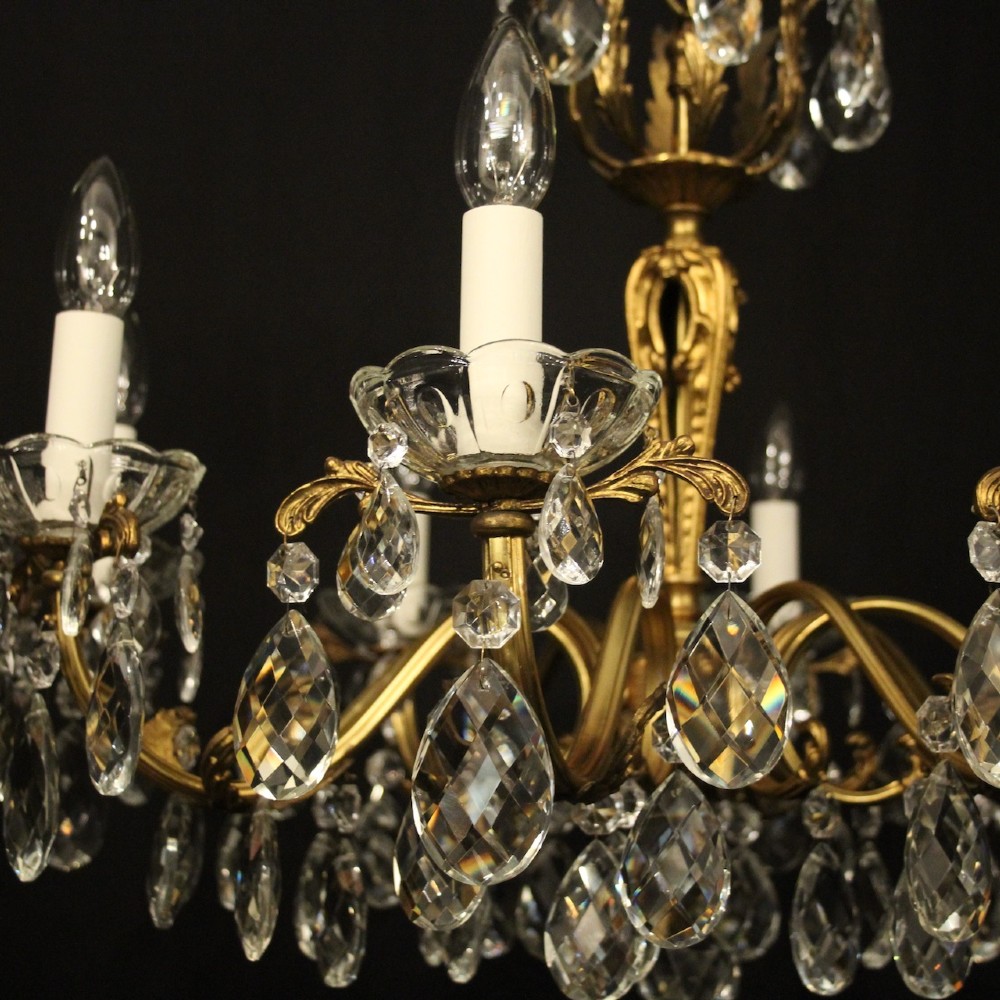 An eight-arm French chandelier featuring a gilded brass frame decorated with hanging cut-crystal glass drops and white candle-style bulb holders. View IV