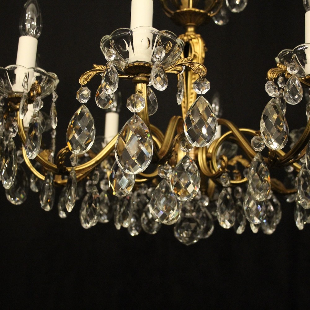 An eight-arm French chandelier featuring a gilded brass frame decorated with hanging cut-crystal glass drops and white candle-style bulb holders. View VI