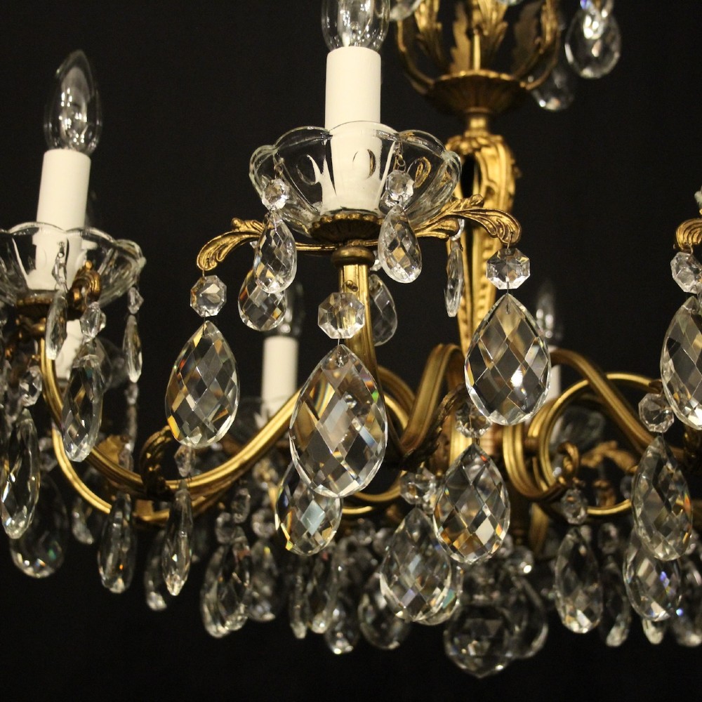 An eight-arm French chandelier featuring a gilded brass frame decorated with hanging cut-crystal glass drops and white candle-style bulb holders. View VII