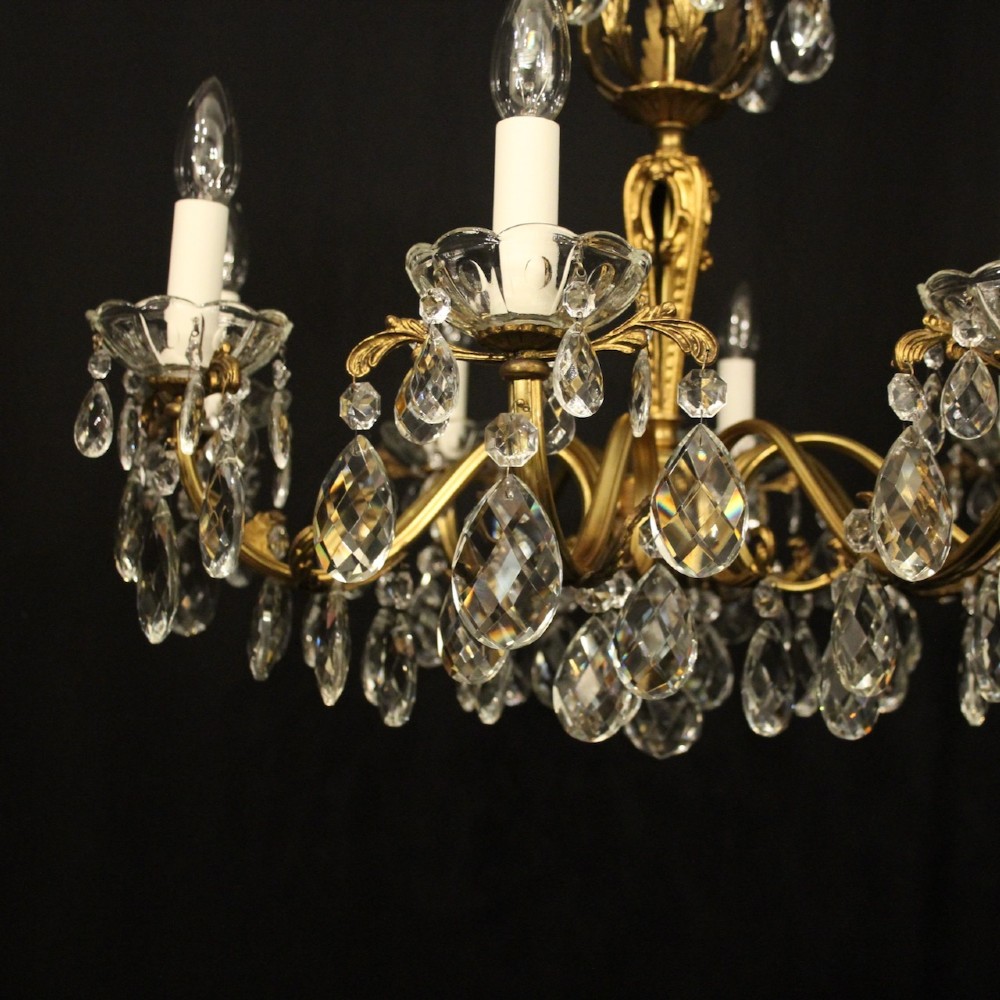 An eight-arm French chandelier featuring a gilded brass frame decorated with hanging cut-crystal glass drops and white candle-style bulb holders. View IX