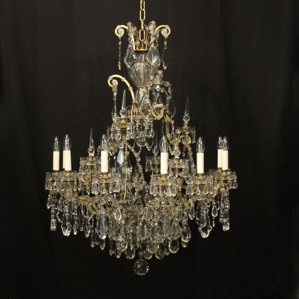 A large French antique twelve-light chandelier featuring a gilded frame dressed with cut crystal teardrop pendants and central glass pinnacles.