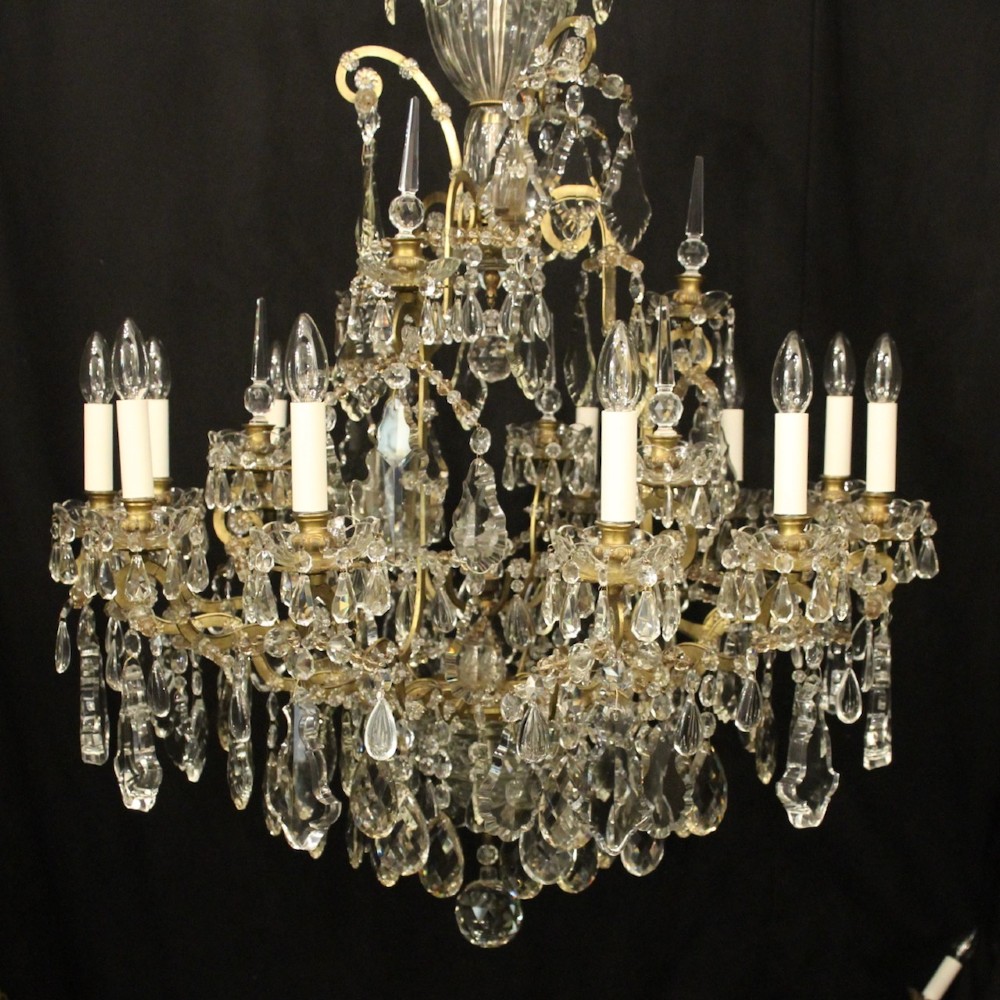 A large French antique twelve-light chandelier featuring a gilded frame dressed with cut crystal teardrop pendants and central glass pinnacles. View II