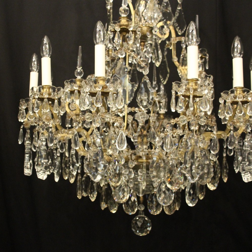 A large French antique twelve-light chandelier featuring a gilded frame dressed with cut crystal teardrop pendants and central glass pinnacles. View IV