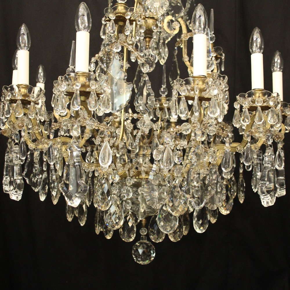 A large French antique twelve-light chandelier featuring a gilded frame dressed with cut crystal teardrop pendants and central glass pinnacles. View V