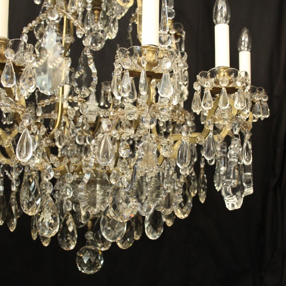 A large French antique twelve-light chandelier featuring a gilded frame dressed with cut crystal teardrop pendants and central glass pinnacles. View VII