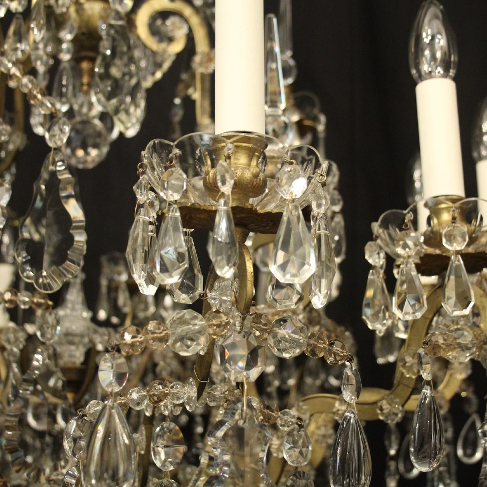 A large French antique twelve-light chandelier featuring a gilded frame dressed with cut crystal teardrop pendants and central glass pinnacles. View VIII