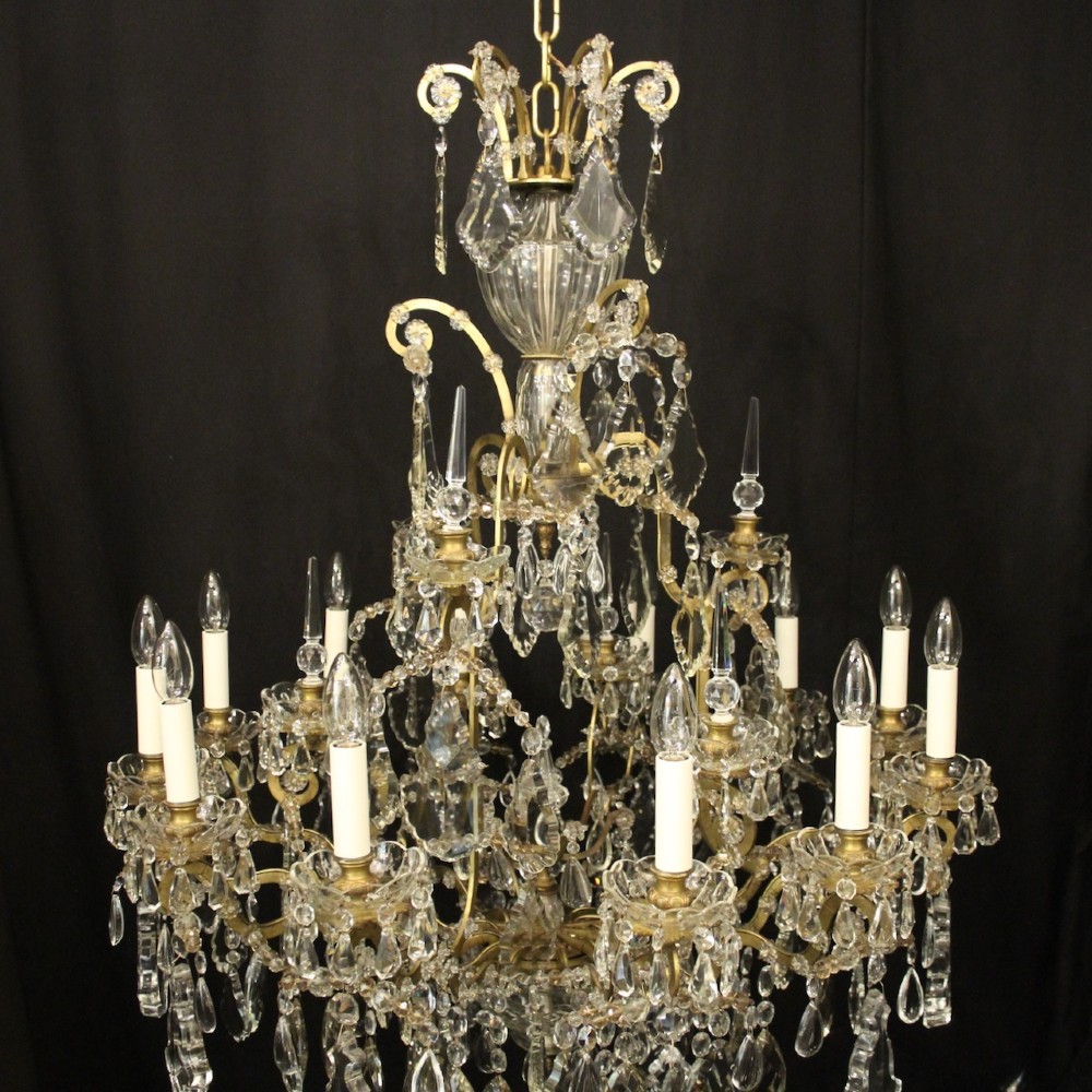 A large French antique twelve-light chandelier featuring a gilded frame dressed with cut crystal teardrop pendants and central glass pinnacles. View IX