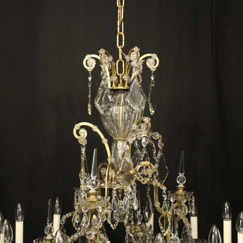 A large French antique twelve-light chandelier featuring a gilded frame dressed with cut crystal teardrop pendants and central glass pinnacles. View X