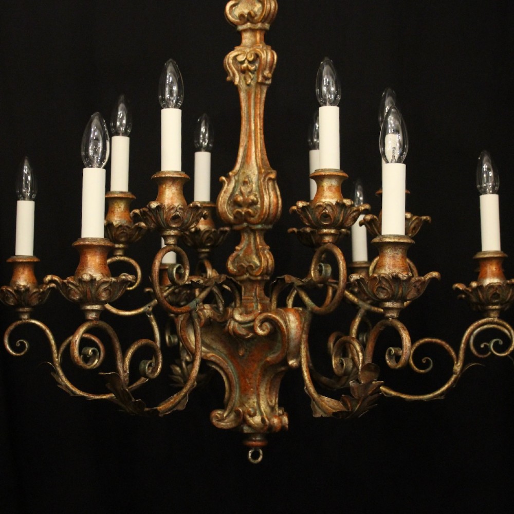 A pair of twelve-light Italian Florentine chandeliers featuring carved gilt wood scrollwork, polychrome painted details, and candle-style bulb holders. View III