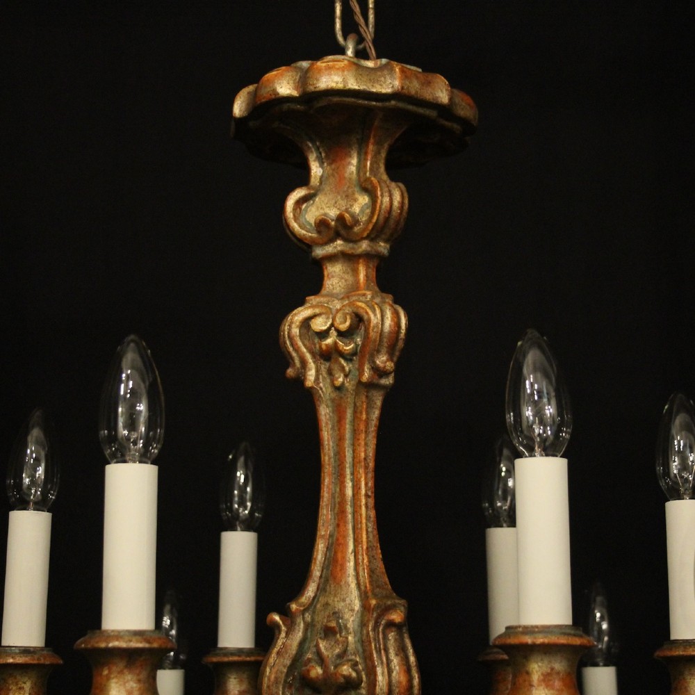 A pair of twelve-light Italian Florentine chandeliers featuring carved gilt wood scrollwork, polychrome painted details, and candle-style bulb holders. View V