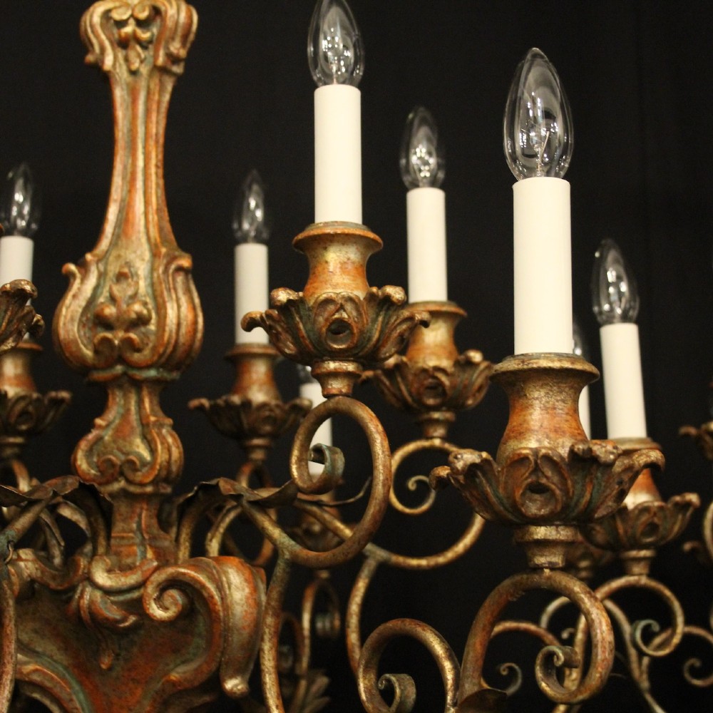 A pair of twelve-light Italian Florentine chandeliers featuring carved gilt wood scrollwork, polychrome painted details, and candle-style bulb holders. View VIII