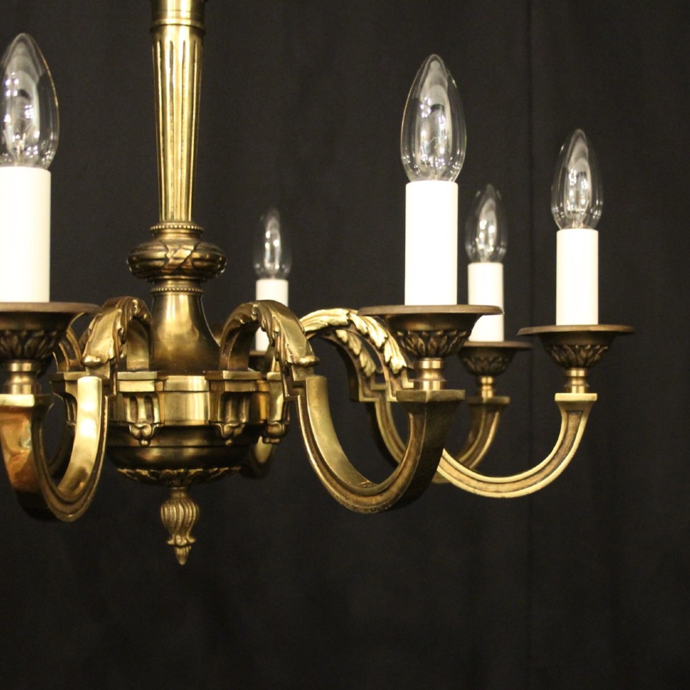 A French gilt bronze six-light chandelier featuring a central fluted stem, scrolled arms with white candle sleeves, and a geometric suspension chain. View III
