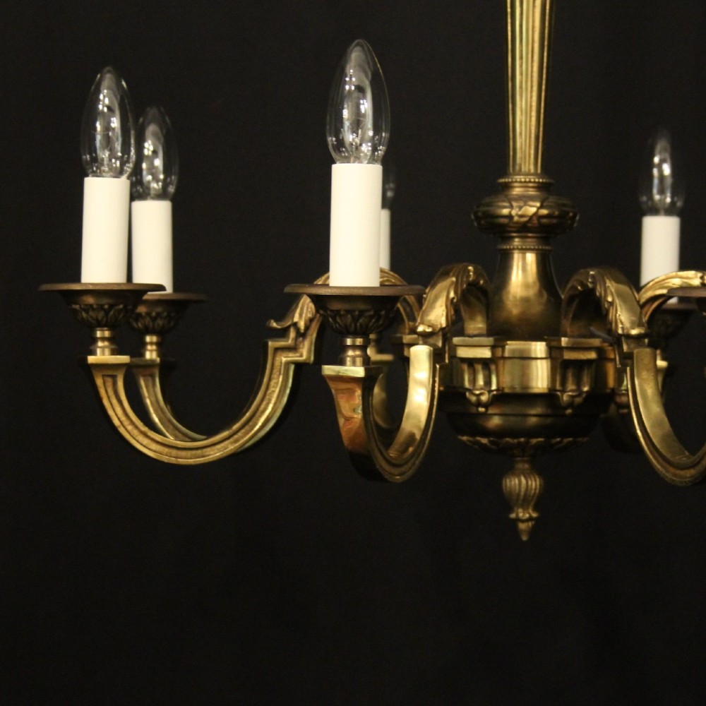 A French gilt bronze six-light chandelier featuring a central fluted stem, scrolled arms with white candle sleeves, and a geometric suspension chain. View IV