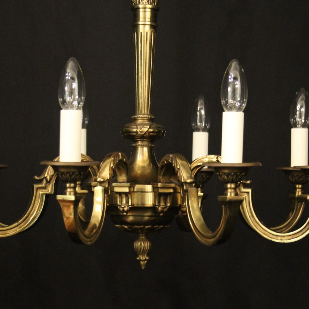 A French gilt bronze six-light chandelier featuring a central fluted stem, scrolled arms with white candle sleeves, and a geometric suspension chain. View VI
