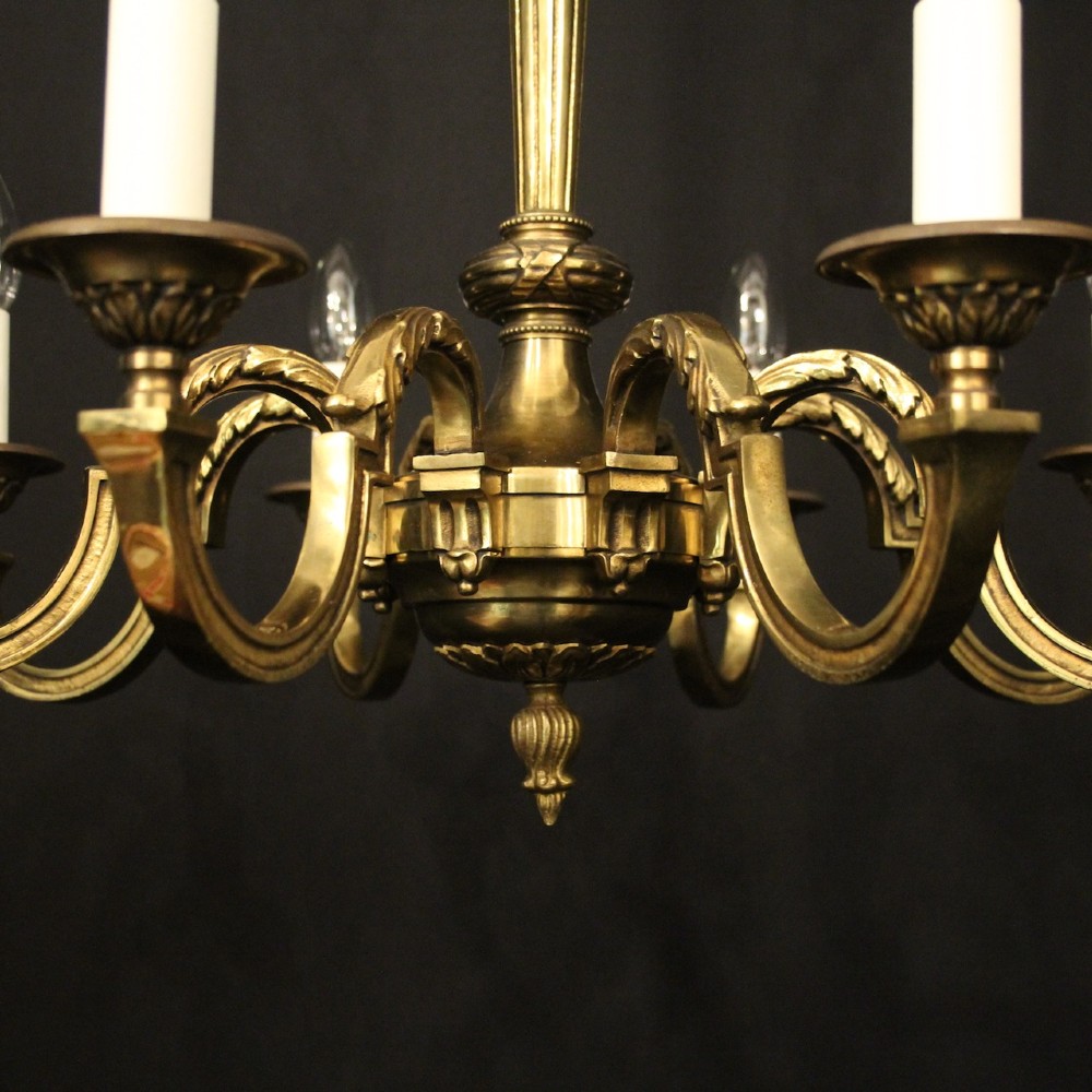 A French gilt bronze six-light chandelier featuring a central fluted stem, scrolled arms with white candle sleeves, and a geometric suspension chain. View VII