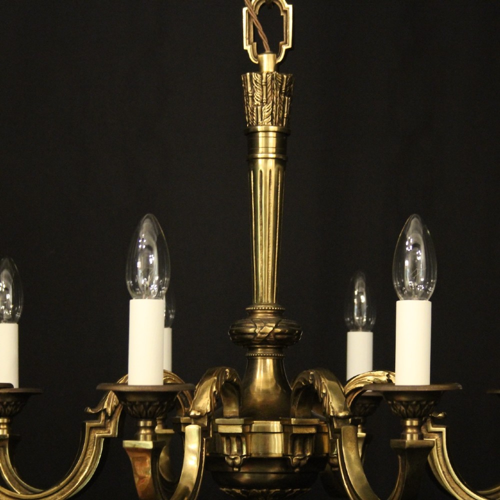 A French gilt bronze six-light chandelier featuring a central fluted stem, scrolled arms with white candle sleeves, and a geometric suspension chain. View VIII