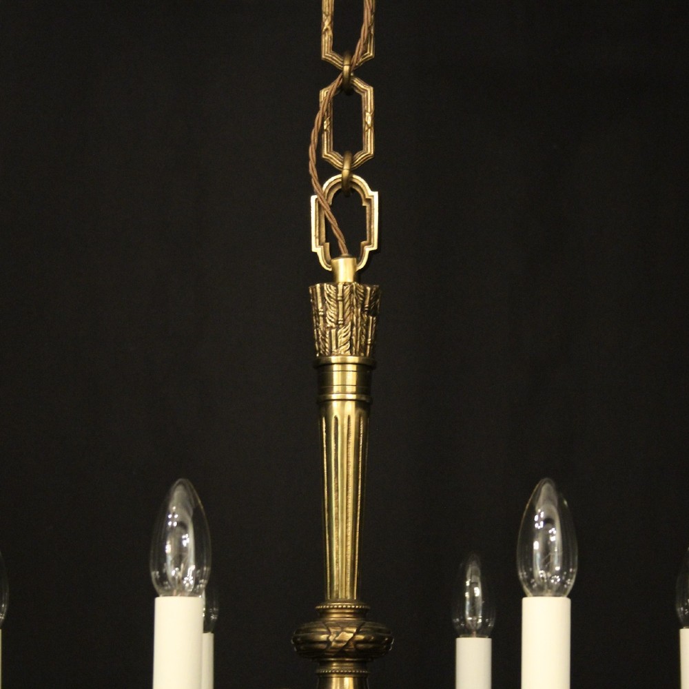 A French gilt bronze six-light chandelier featuring a central fluted stem, scrolled arms with white candle sleeves, and a geometric suspension chain. View IX